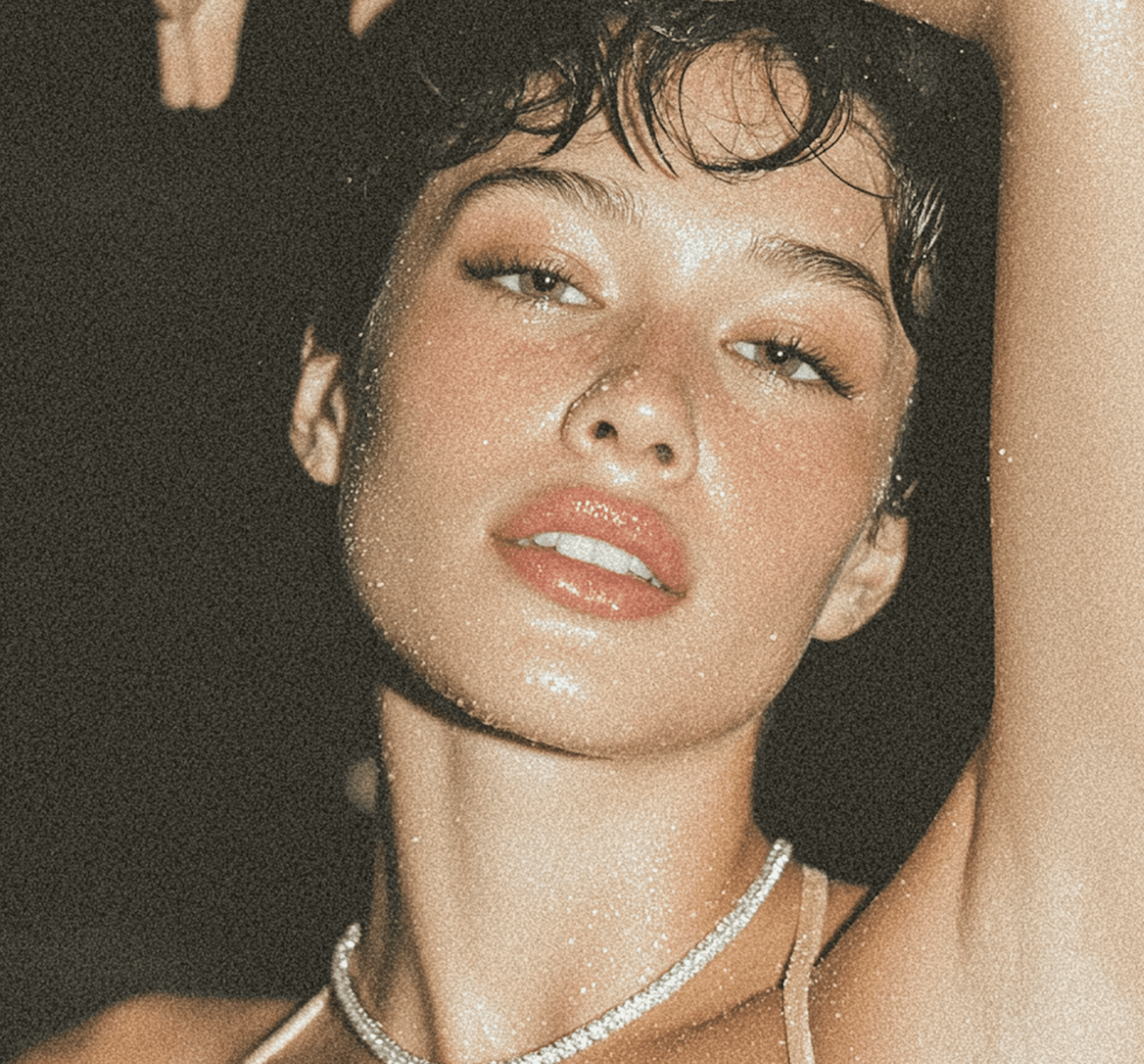 Person with wet skin, short hair, and raised arm in sparkly necklace